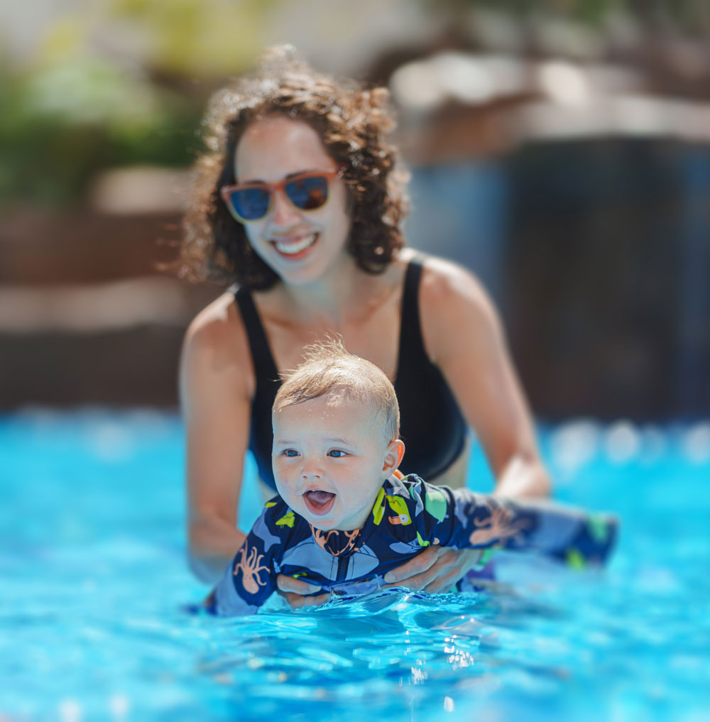 Mother holding smiling baby in swimming pool