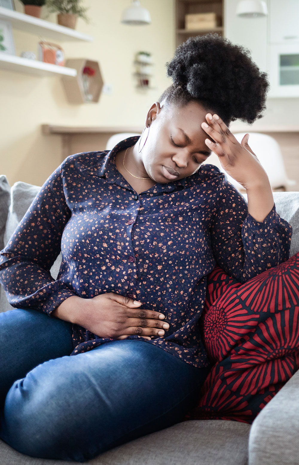 Woman with stomachache looking unwell on couch