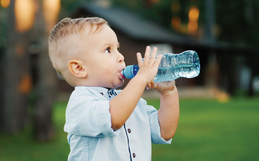 Young boy drinking water from bottle outdoors