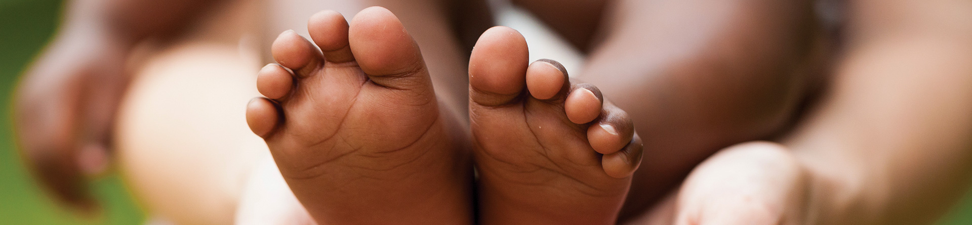 Baby feet held gently in adult hands