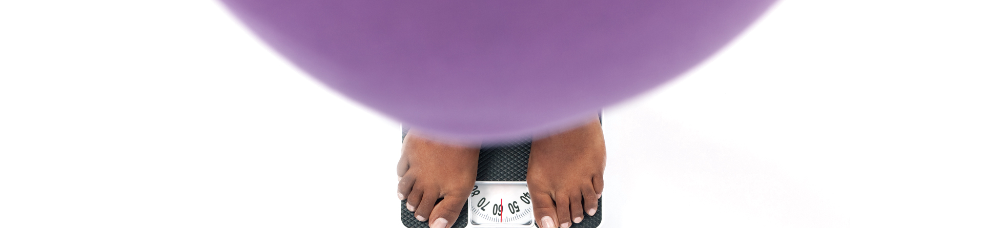 Feet standing on scale, obscured by purple exercise ball