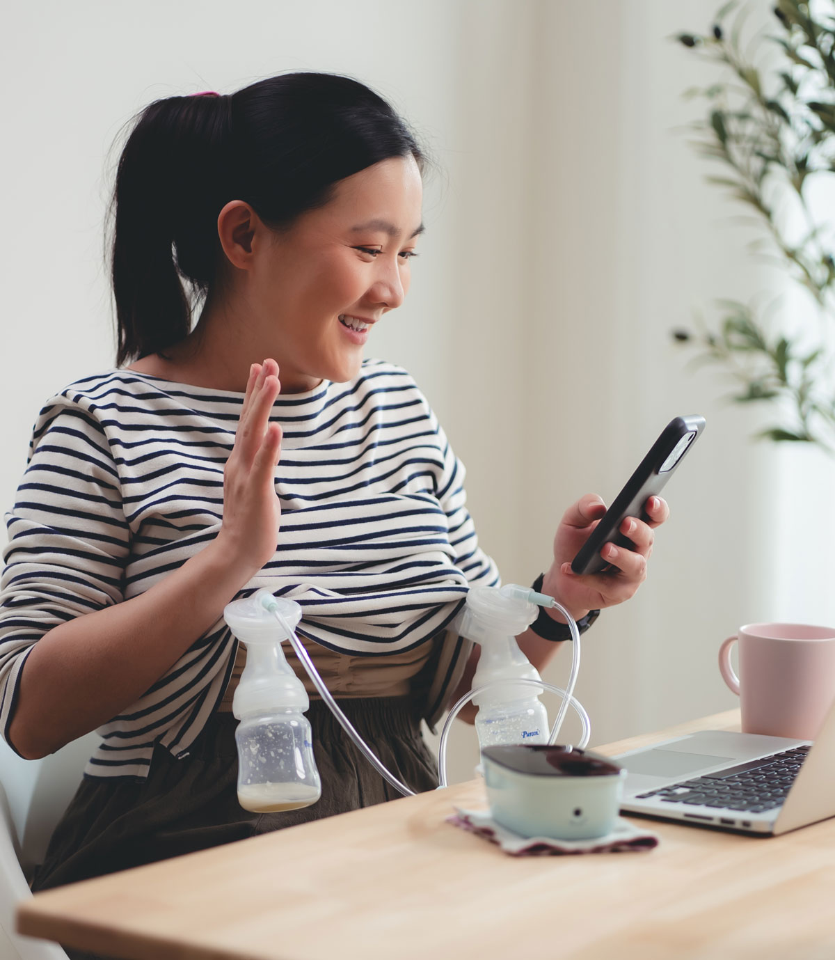 Mother using a breast pump while video calling on smartphone
