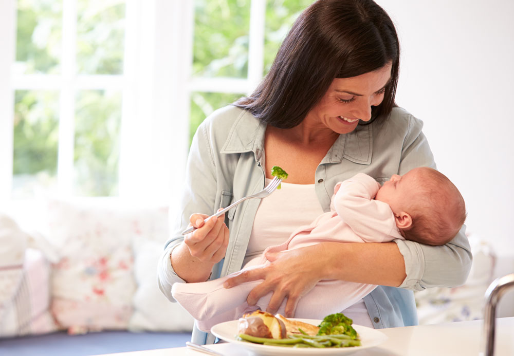 Mother eating while holding baby