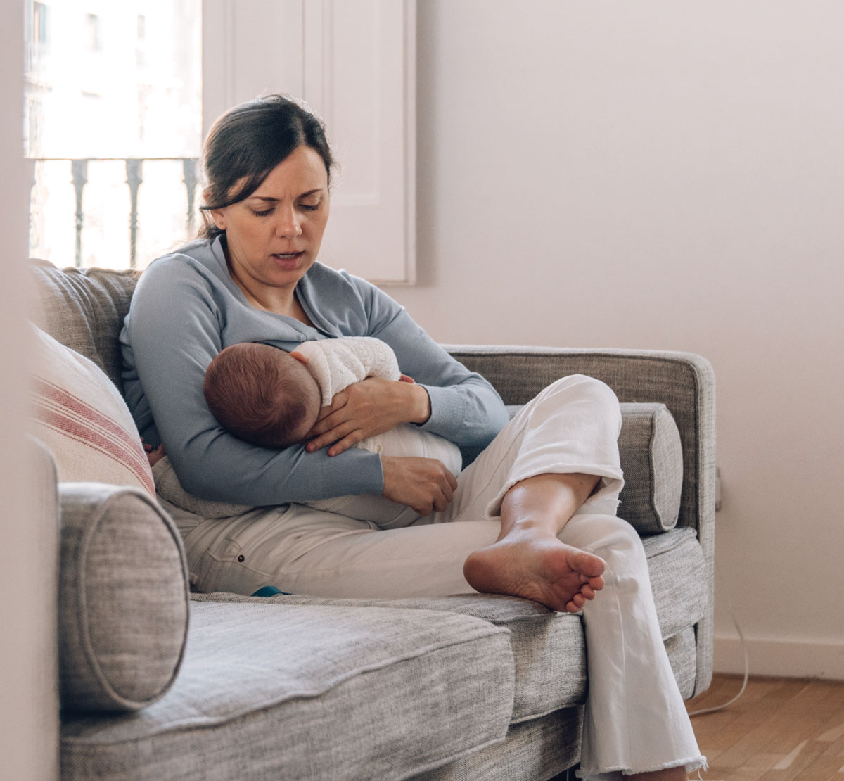 Mother breastfeeding baby on a cozy couch