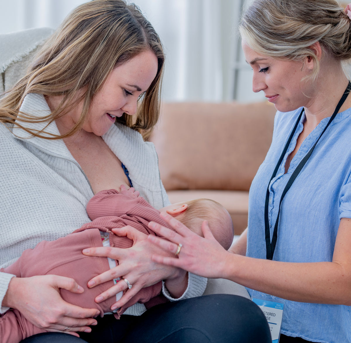 Mother breastfeeding baby with nurse support and guidance