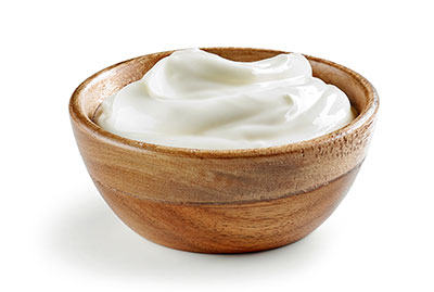 Wooden bowl filled with creamy yogurt.