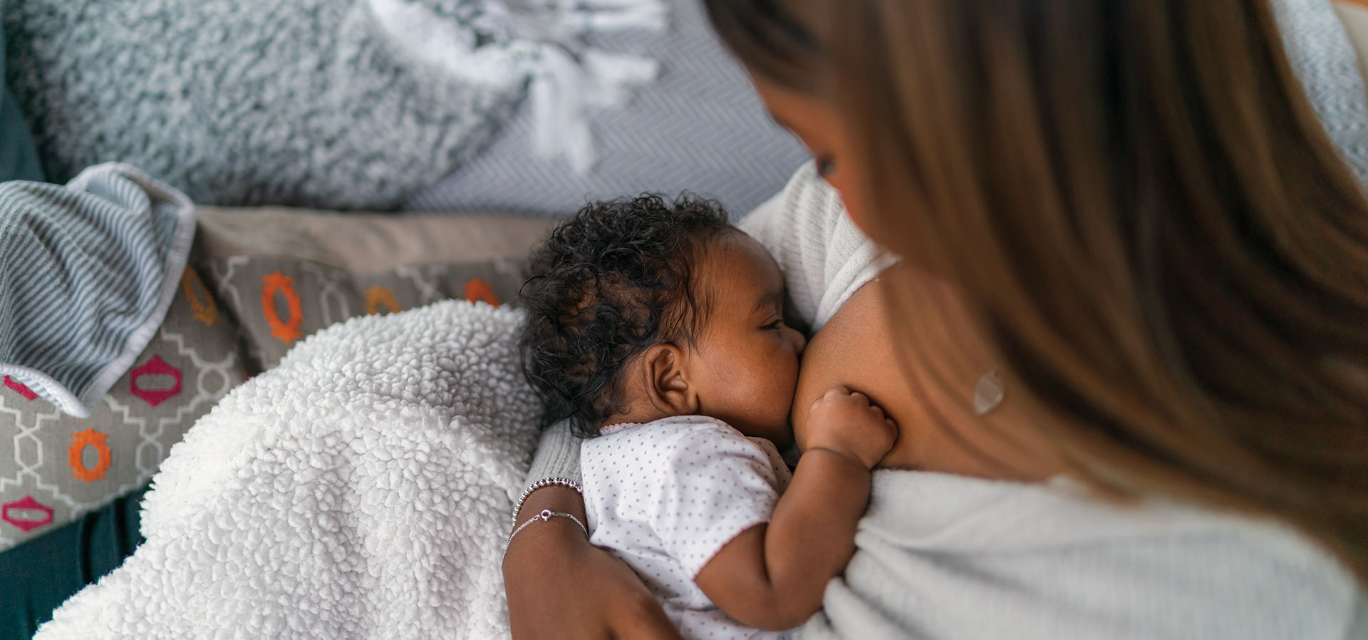 Mother breastfeeding infant on cozy couch