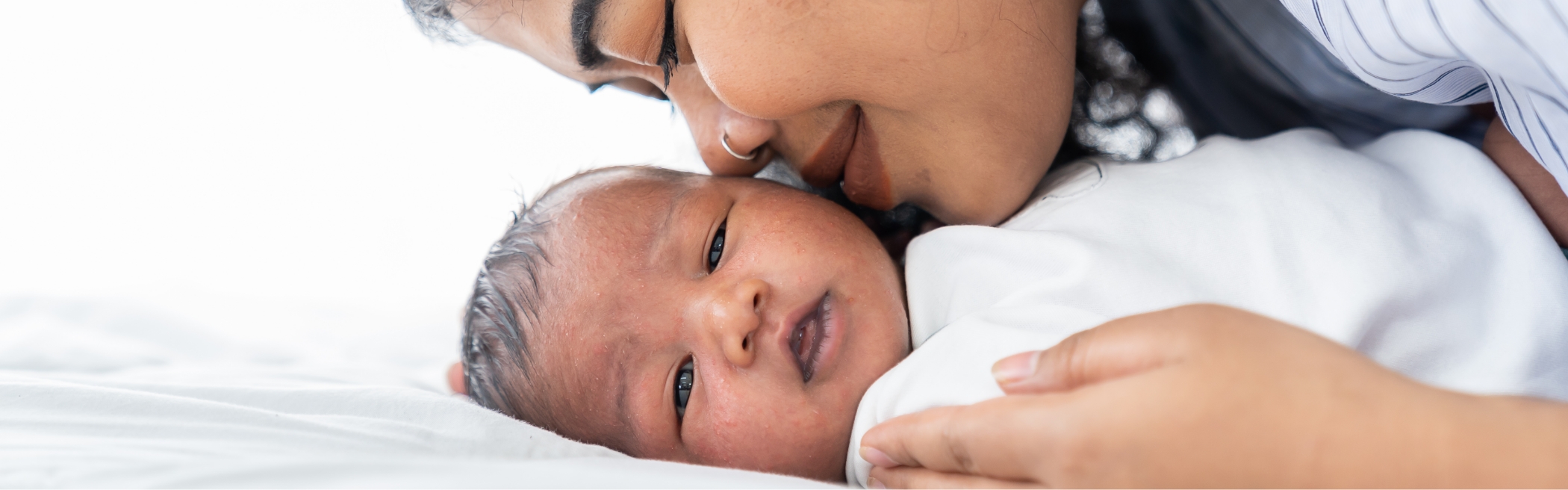 Mother gently kisses her newborn on the forehead