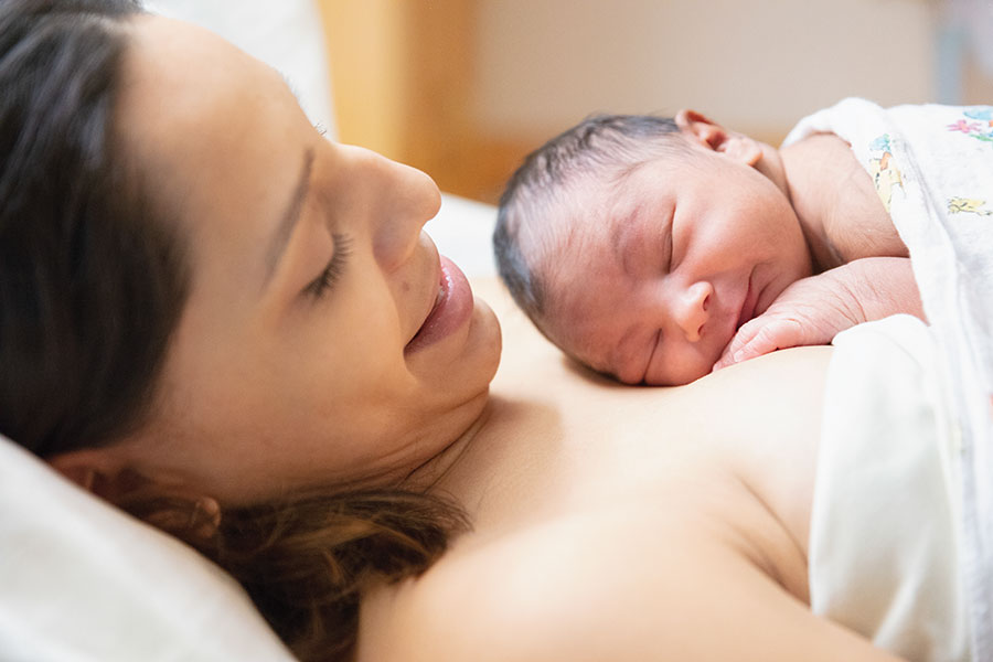 Mother smiling with newborn baby resting on chest