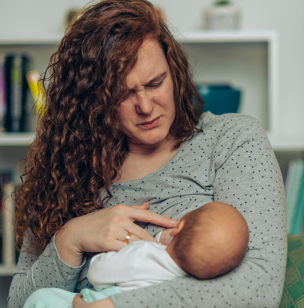 Mother in pain breastfeeding her baby