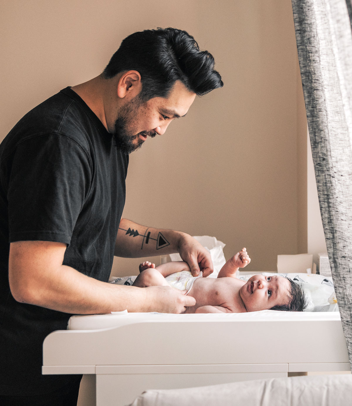 Father changing baby on a diaper changing table
